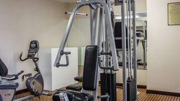 A gym with a variety of equipment including a treadmill, a weight machine, and a mirror.