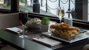 A dining table with a glass of red wine, a bowl of salad, a small plant, and a basket of fish and chips. - Copthorne Hotel Manchester Salford Quays (Salford)