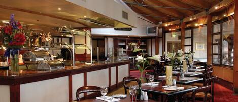 A restaurant with wooden furniture, a buffet area, and a high ceiling with exposed beams.