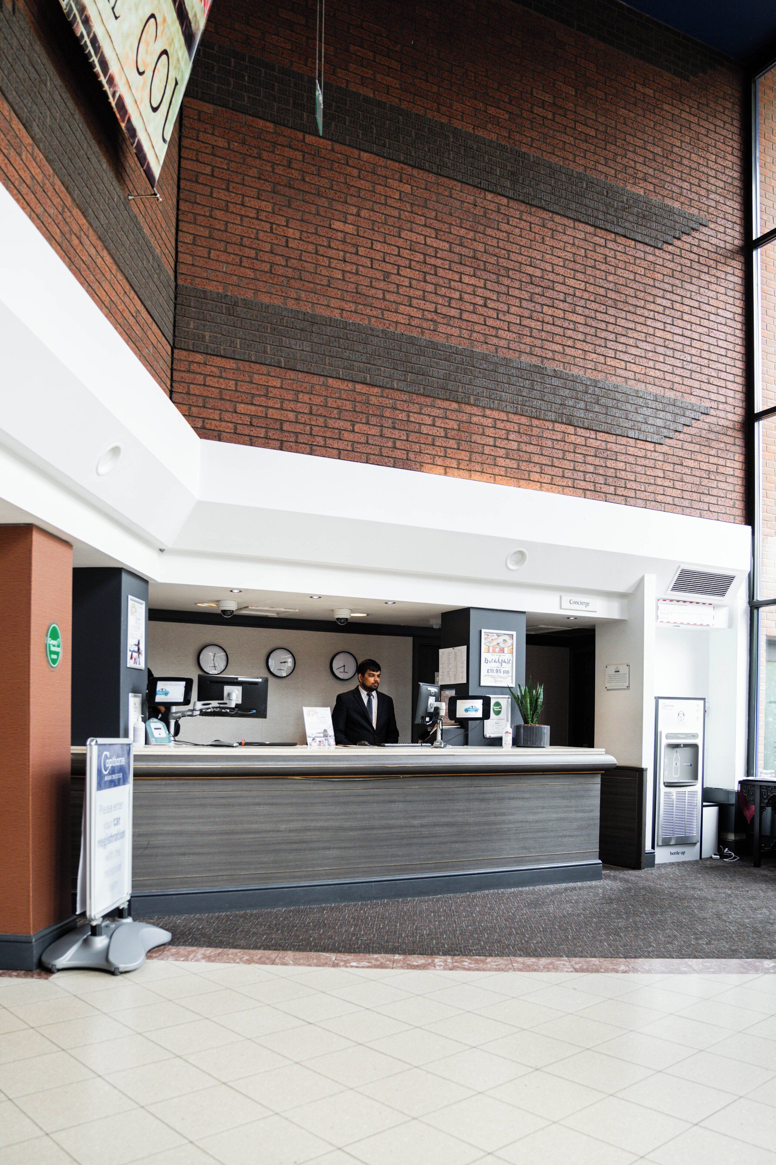 A reception desk with a receptionist, a clock, and a sign indicating a conference room.
