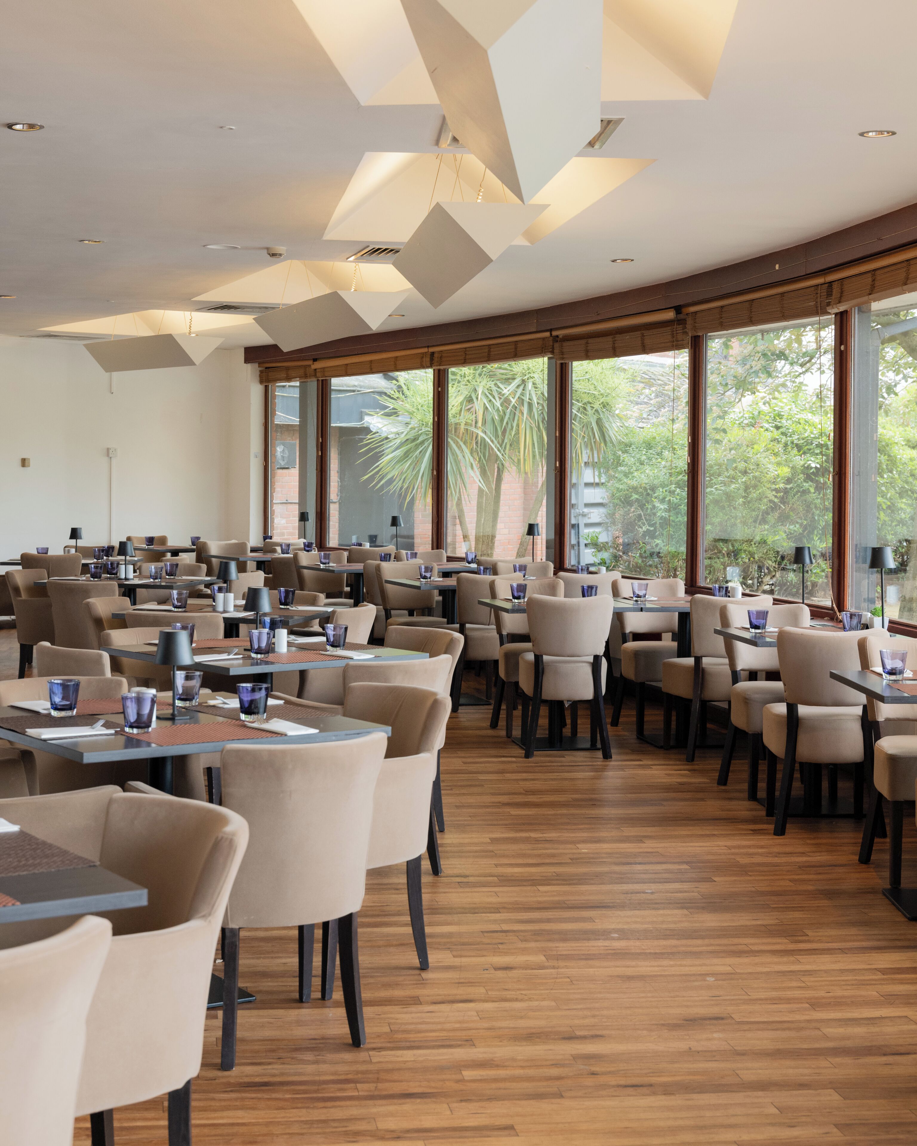 Ein geräumiges Restaurant mit hohen Decken, großen Fenstern und modernem Interieur.