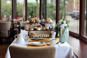 A table set for a tea service with a tiered display of pastries, a teapot, cups, and a vase with flowers. - Copthorne Hotel Manchester Salford Quays (Salford)