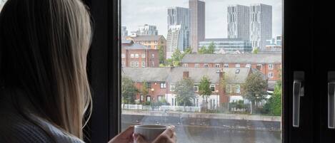A person sitting by a window with a view of a river and buildings.