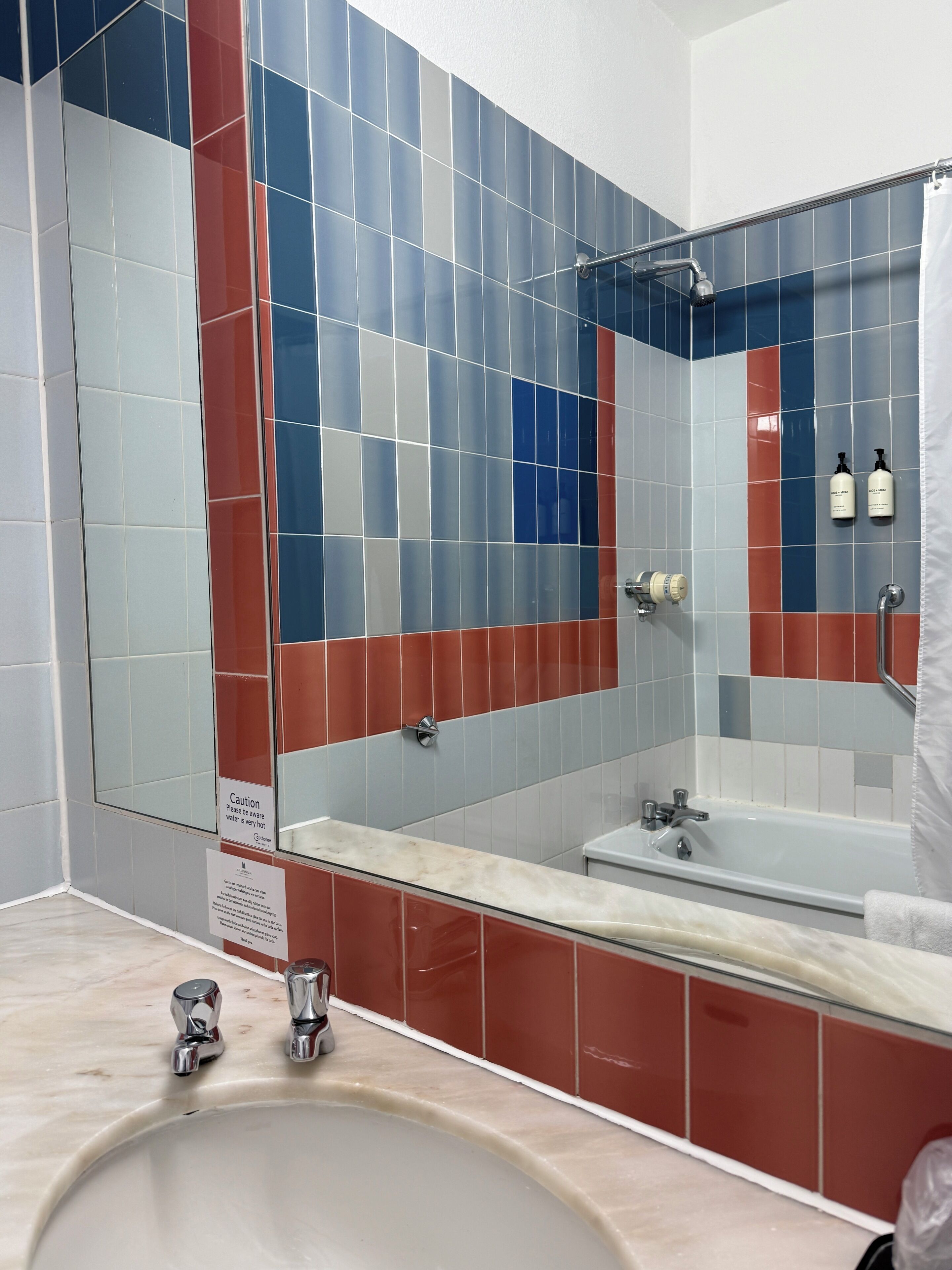 A bathroom with a sink, mirror, and shower area.