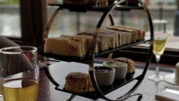 Un carrito de postres con diferentes pasteles y una copa de vino sobre una mesa.