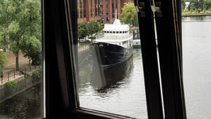 A view from a window overlooking a river with a boat, a red brick building, and a modern building across the water. - Copthorne Hotel Manchester Salford Quays (Salford)