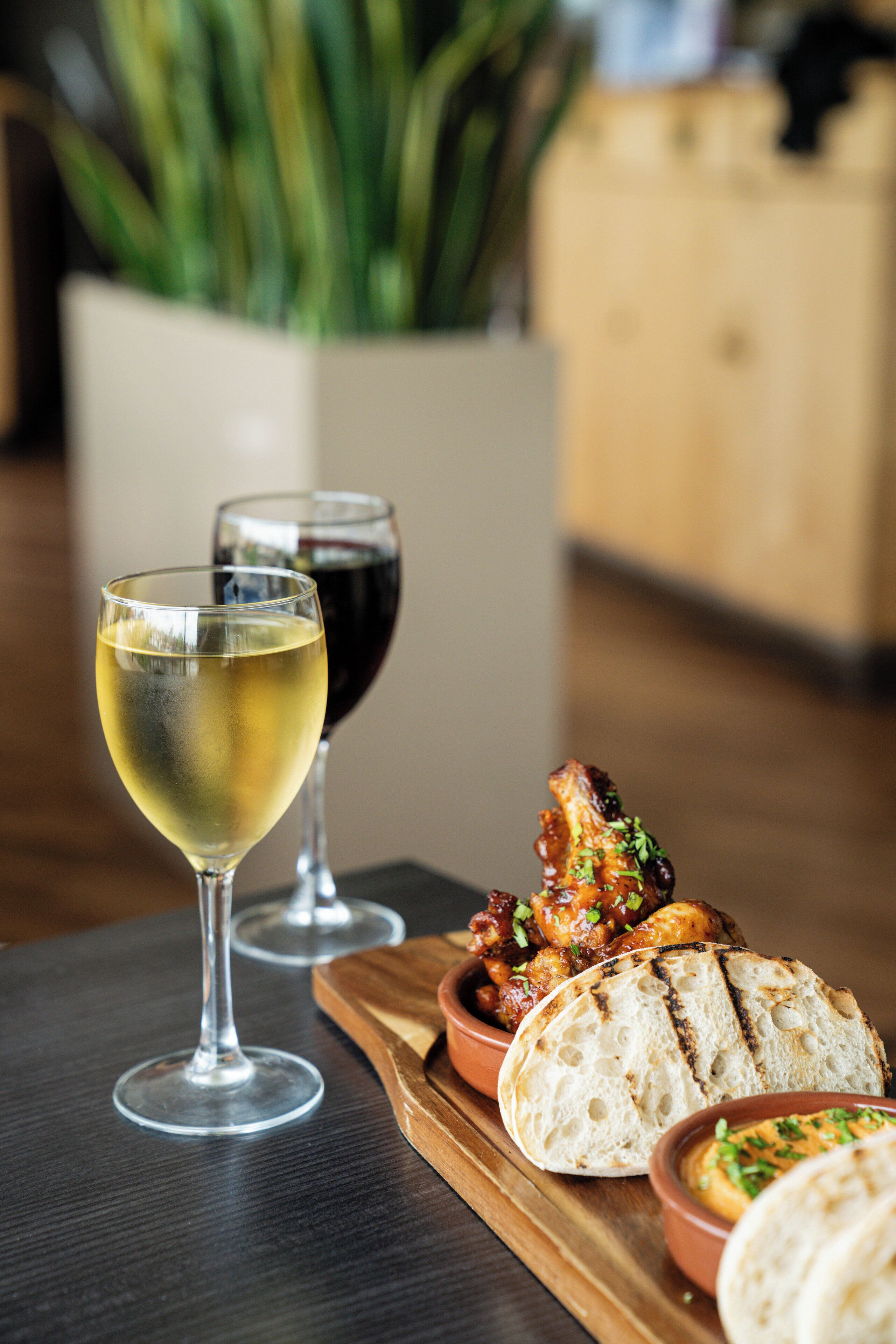 A dining table with two wine glasses, a bowl of food, and a loaf of bread.