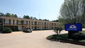 A motel with a parking lot, a sign indicating 'ENTER', and a vehicle parked in front.