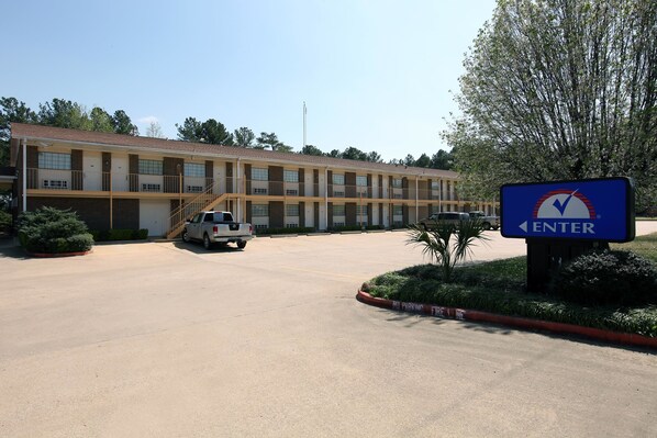 A motel with a parking lot, a sign indicating 'ENTER', and a vehicle parked in front. - Country Side Inn (Tyler)