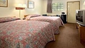 A hotel room with two beds, a desk, a chair, a television, and a window with curtains.
