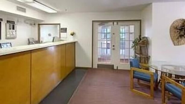 A reception area with a wooden counter, a reception desk, a door with glass panels, and a blue chair.