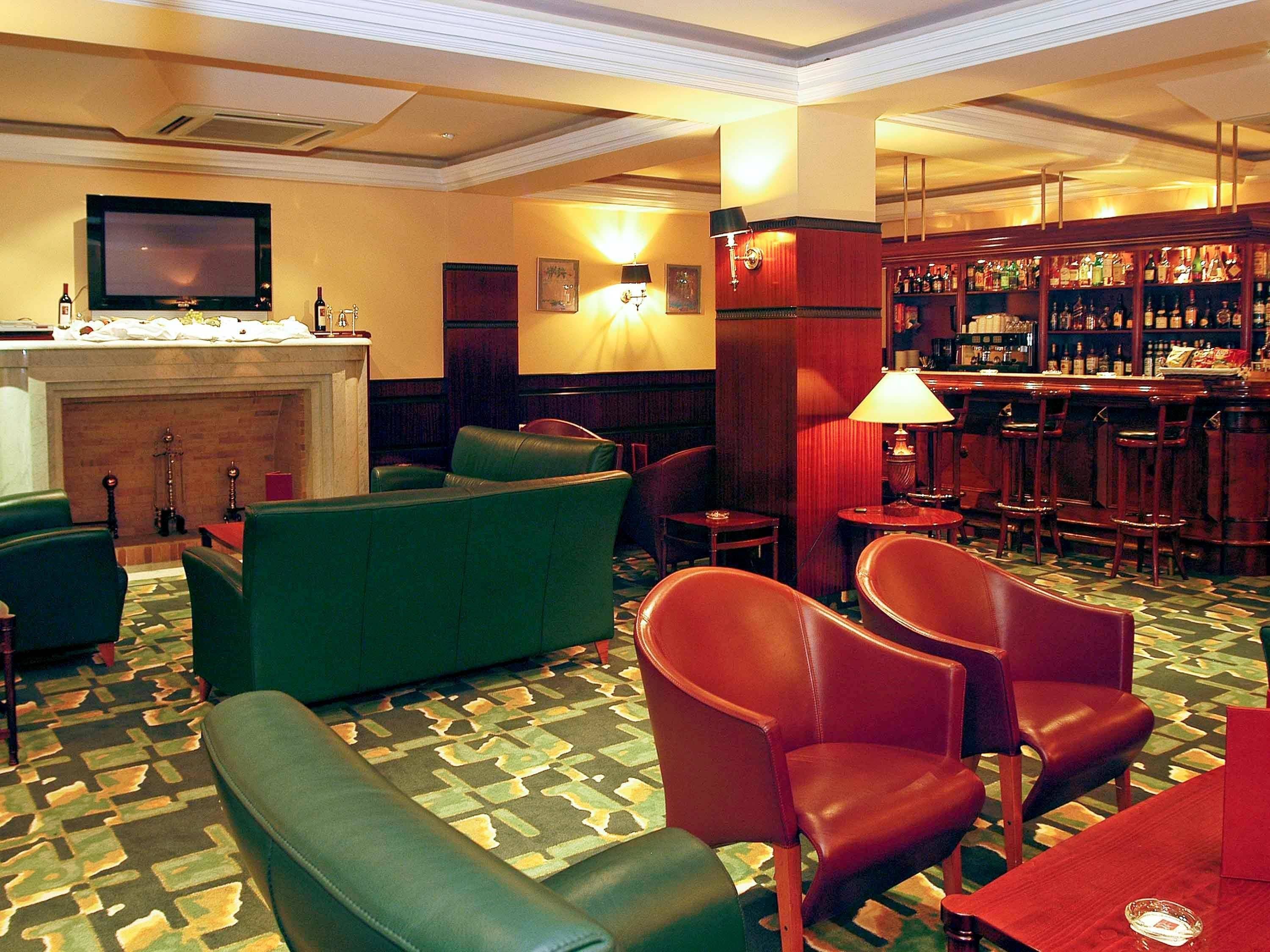 A bar area with leather seating, a television, and a fireplace.