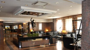 A spacious lobby with a reception desk, seating area, and a decorative statue. - Mercure Andorra (Andorra la Vella)