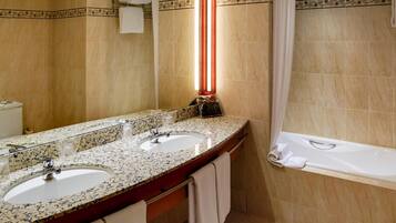 Un baño con dos lavamanos, un espejo grande, una bañera y un perchero para toallas.