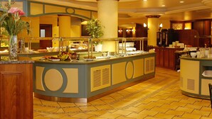 A buffet area with a central island, a large column, and a tiled floor. - Mercure Andorra (Andorra la Vella)