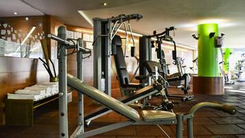 A gym with various exercise machines, a green pillar, and a tiled floor.