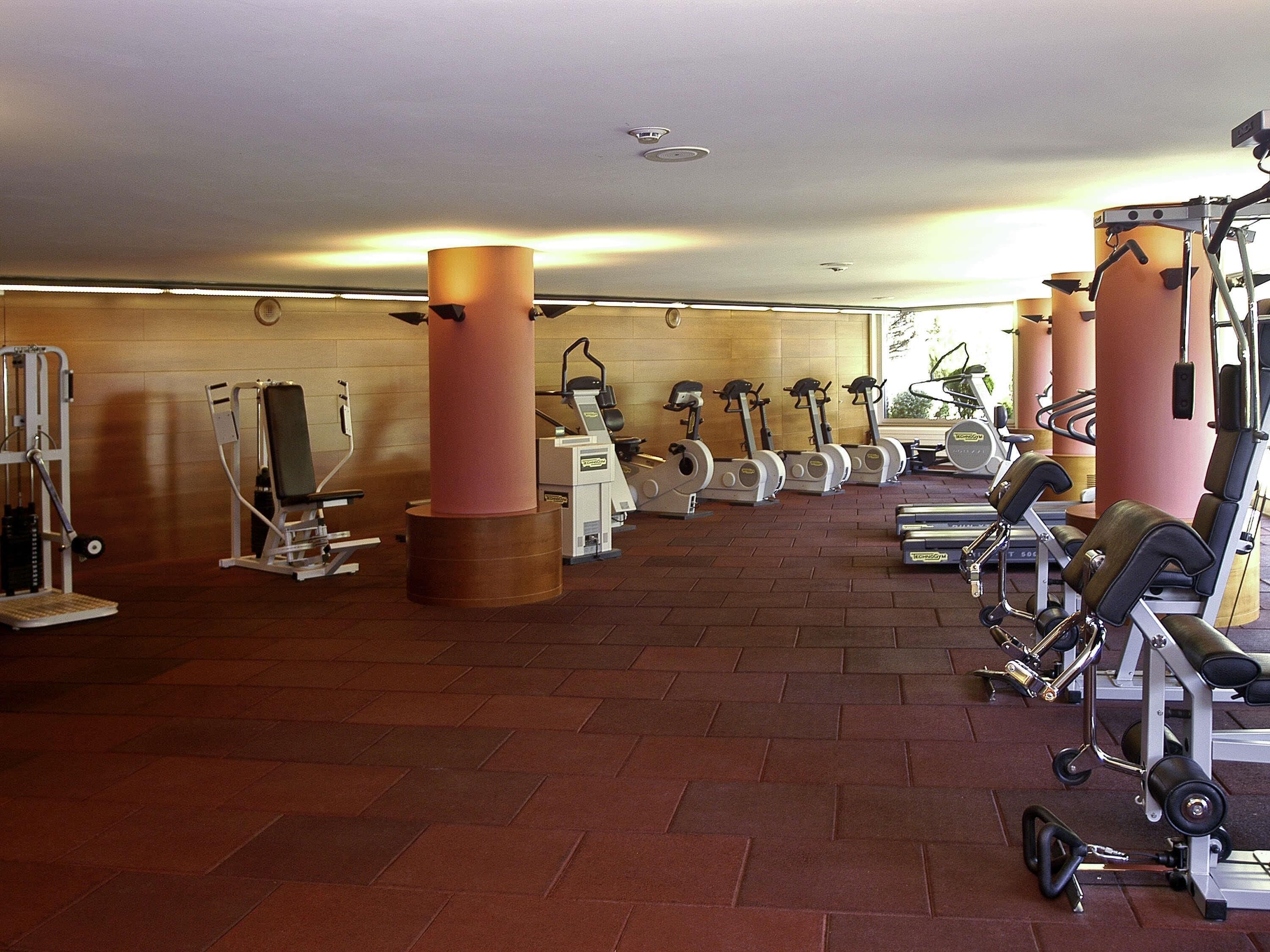 Une salle de sport équipée de divers appareils d’exercice, notamment des tapis de course, des vélos d’appartement et des appareils de musculation.