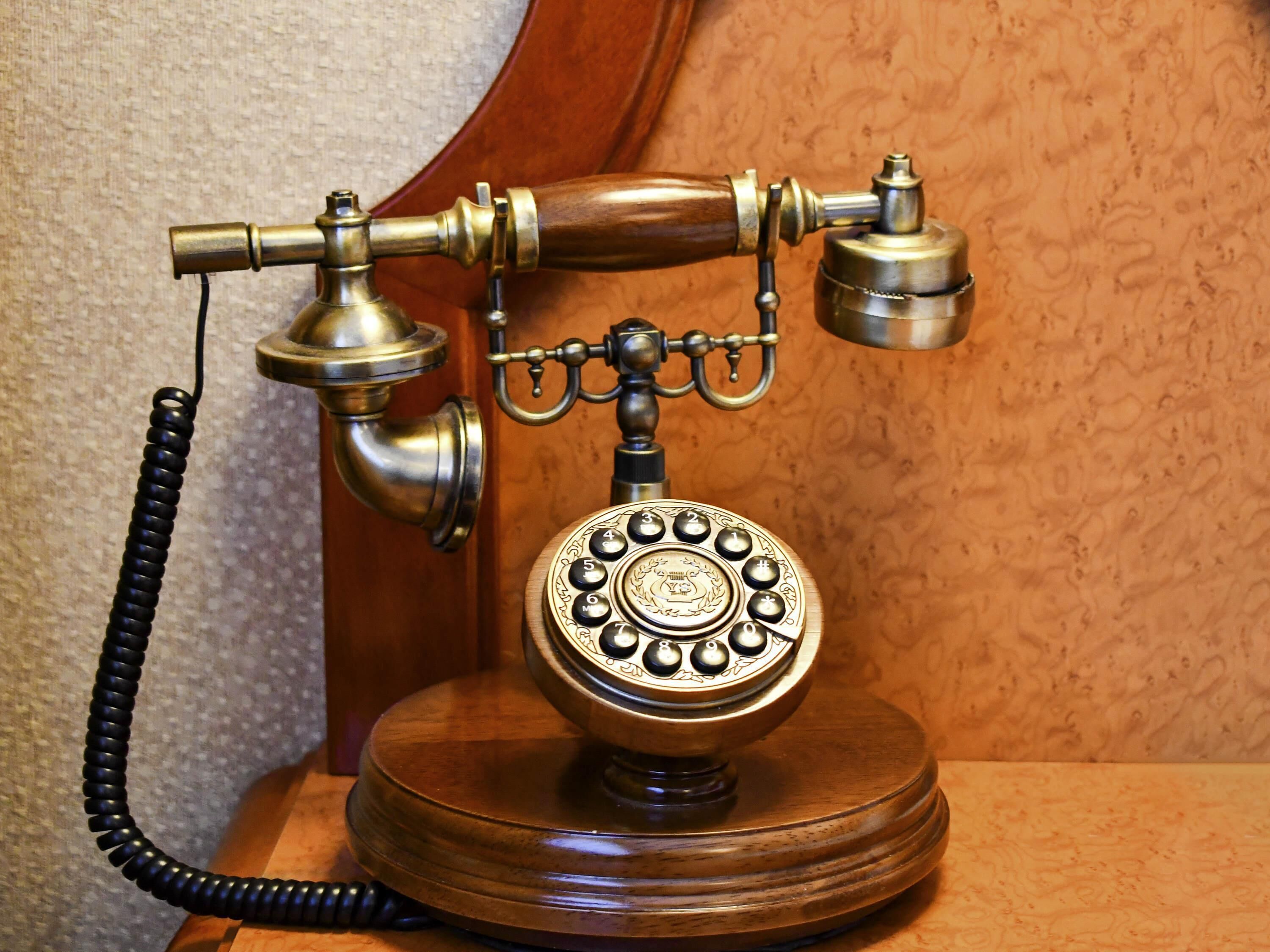 Un telefono a disco vintage con cavo a spirale, montato su una base di legno.