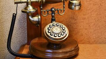Un telefono a disco vintage con cavo a spirale, montato su una base di legno.