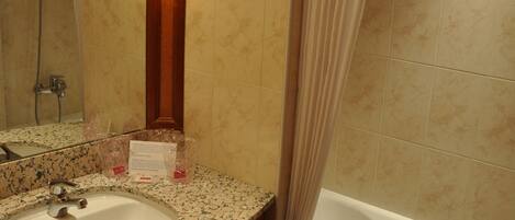 Un baño con lavamanos, espejo y bañera.