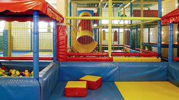 An indoor play area with padded play structures, a ball pit, and a climbing net.