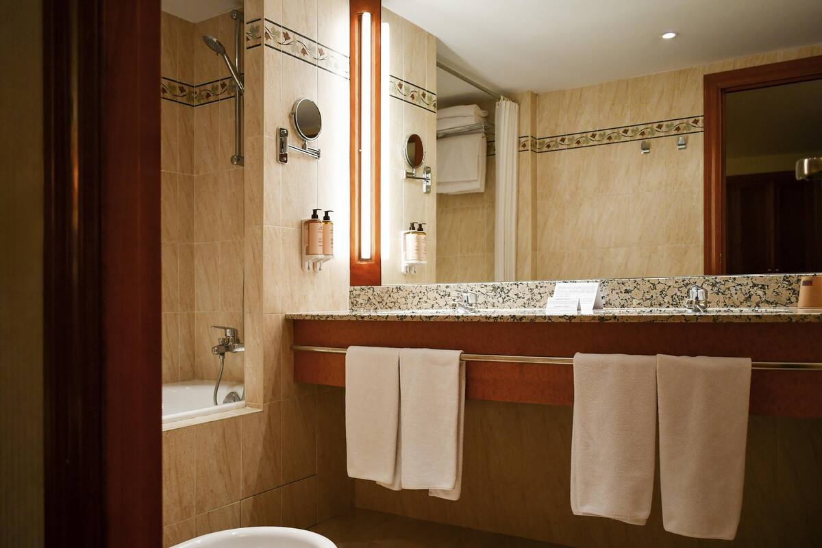A bathroom with a bathtub, a sink with a mirror, and a toilet.