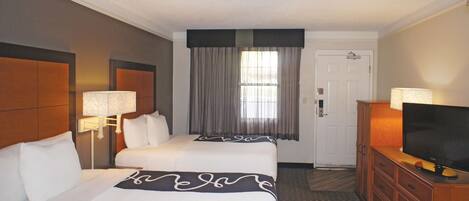 A hotel room with two beds, a television, and a door.