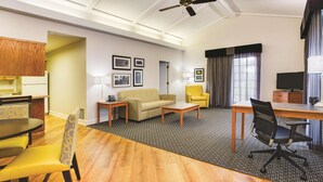 A hotel room with a dining area, a sofa, a TV, and a ceiling fan. - Days Inn by Wyndham Gainesville University I-75 (Gainesville)