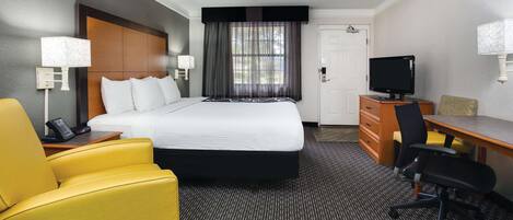 Habitación de hotel con cama, escritorio, silla, televisor y teléfono.