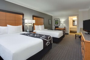A hotel room with two beds, a desk, a chair, a television, and a bathroom visible through an open door. - Days Inn by Wyndham Gainesville University I-75 (Gainesville)