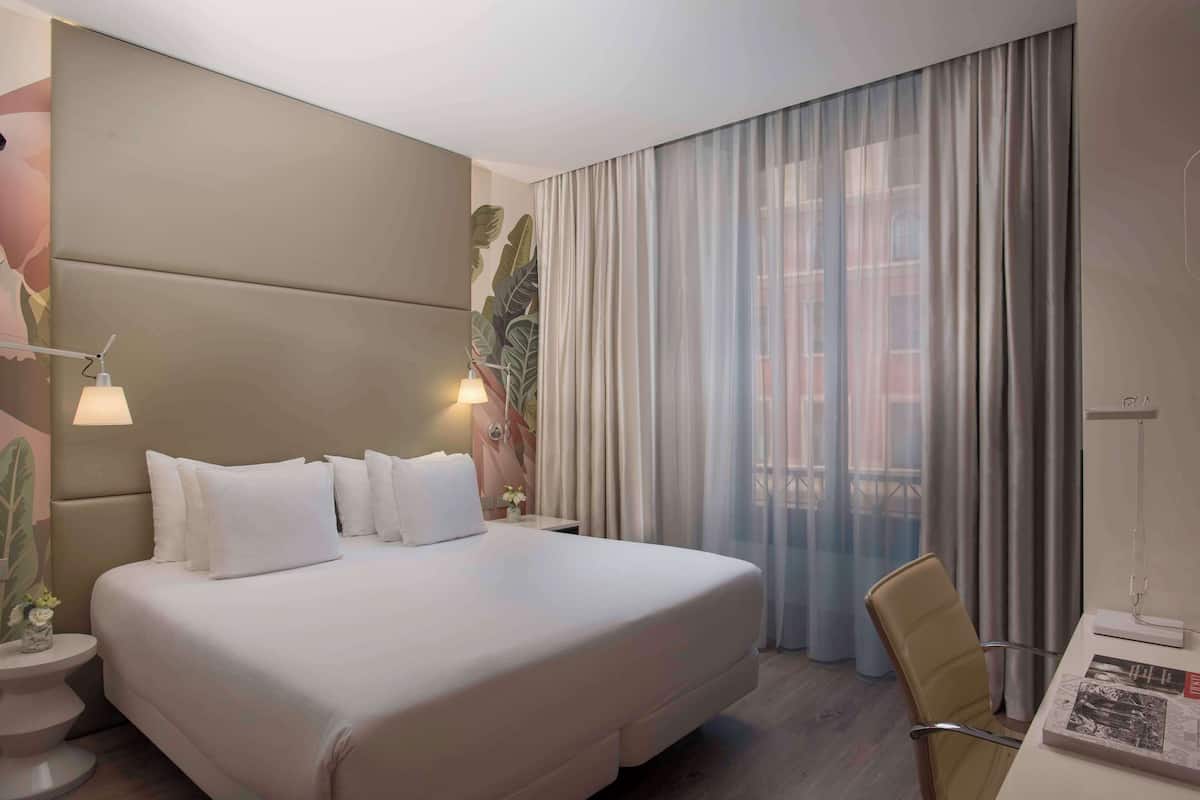 Una habitación de hotel moderna con una cama grande, un escritorio y una silla.