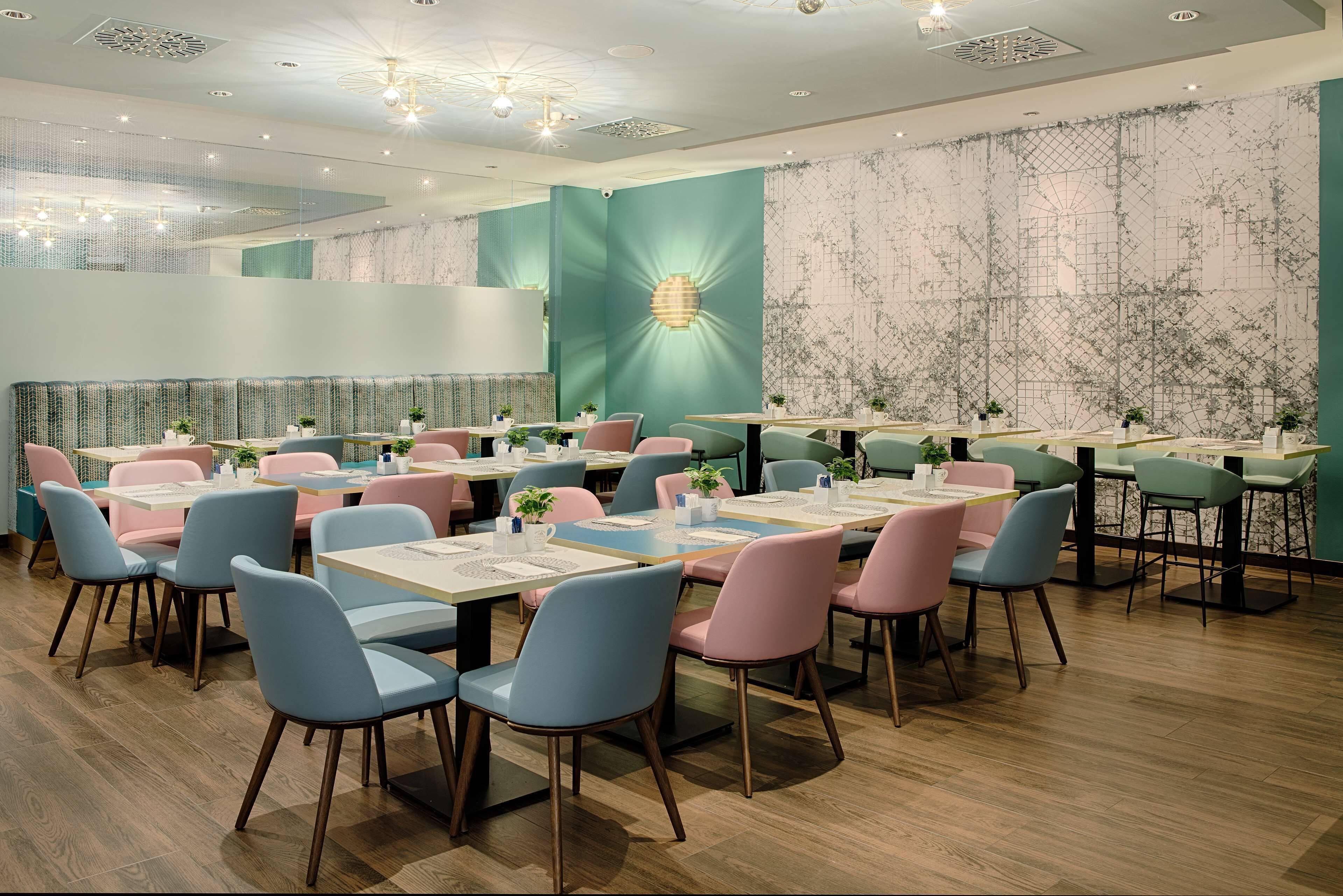 A modern restaurant with multiple tables and chairs, a patterned wall, and a ceiling with recessed lighting.