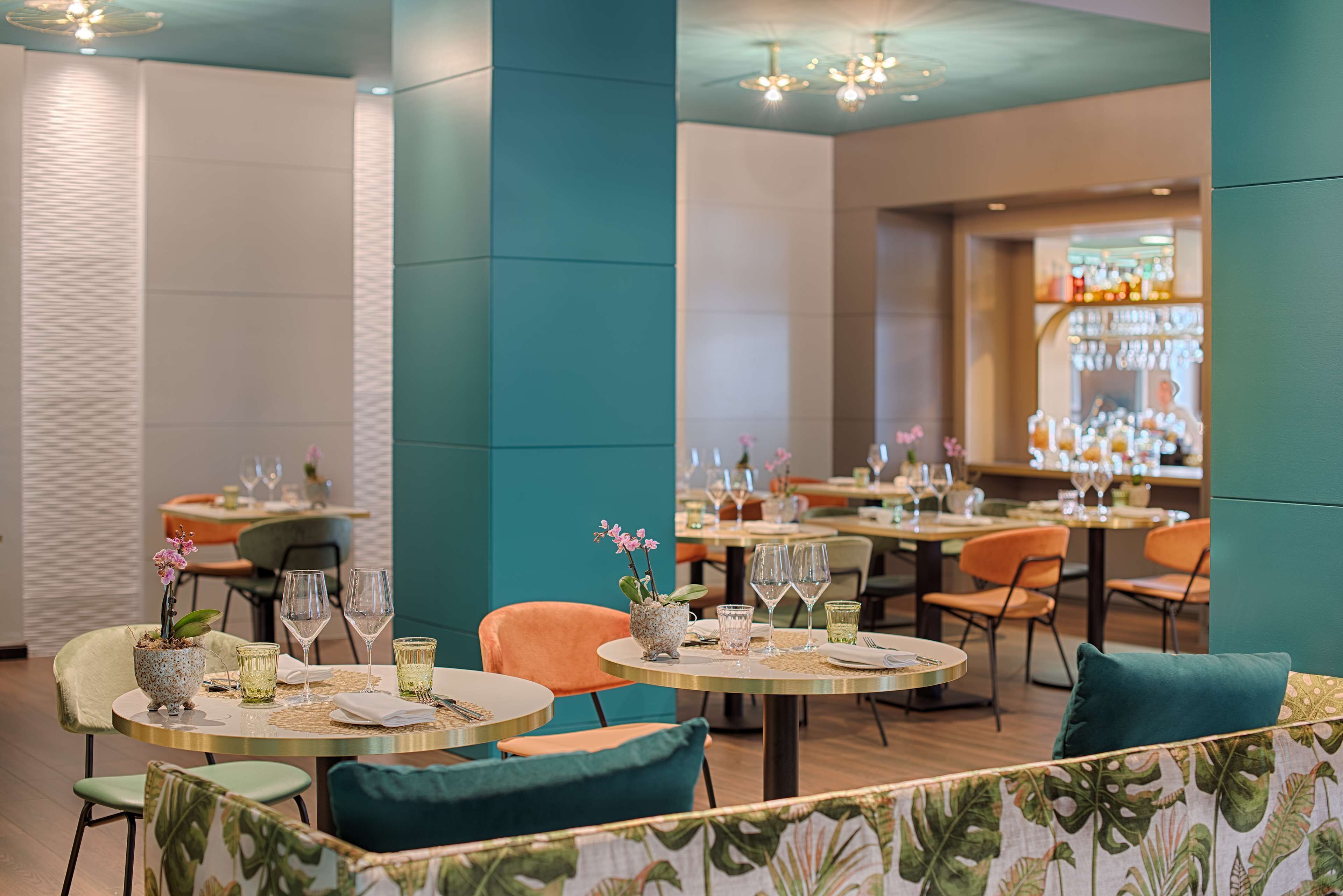 A restaurant with round tables, chairs, and a bar area.