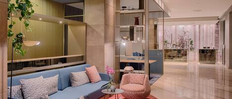 A modern living room with a blue sofa, patterned armchairs, and a red rug.