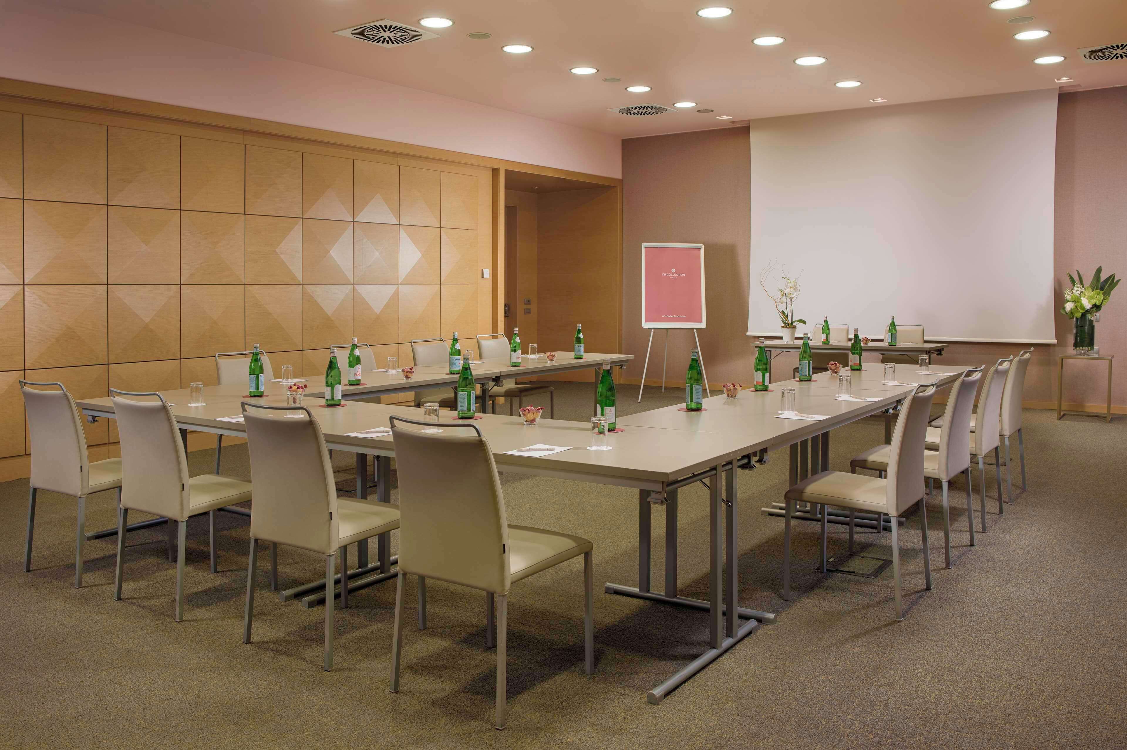 Una sala conferenze con un lungo tavolo, sedie e uno schermo per proiezioni.