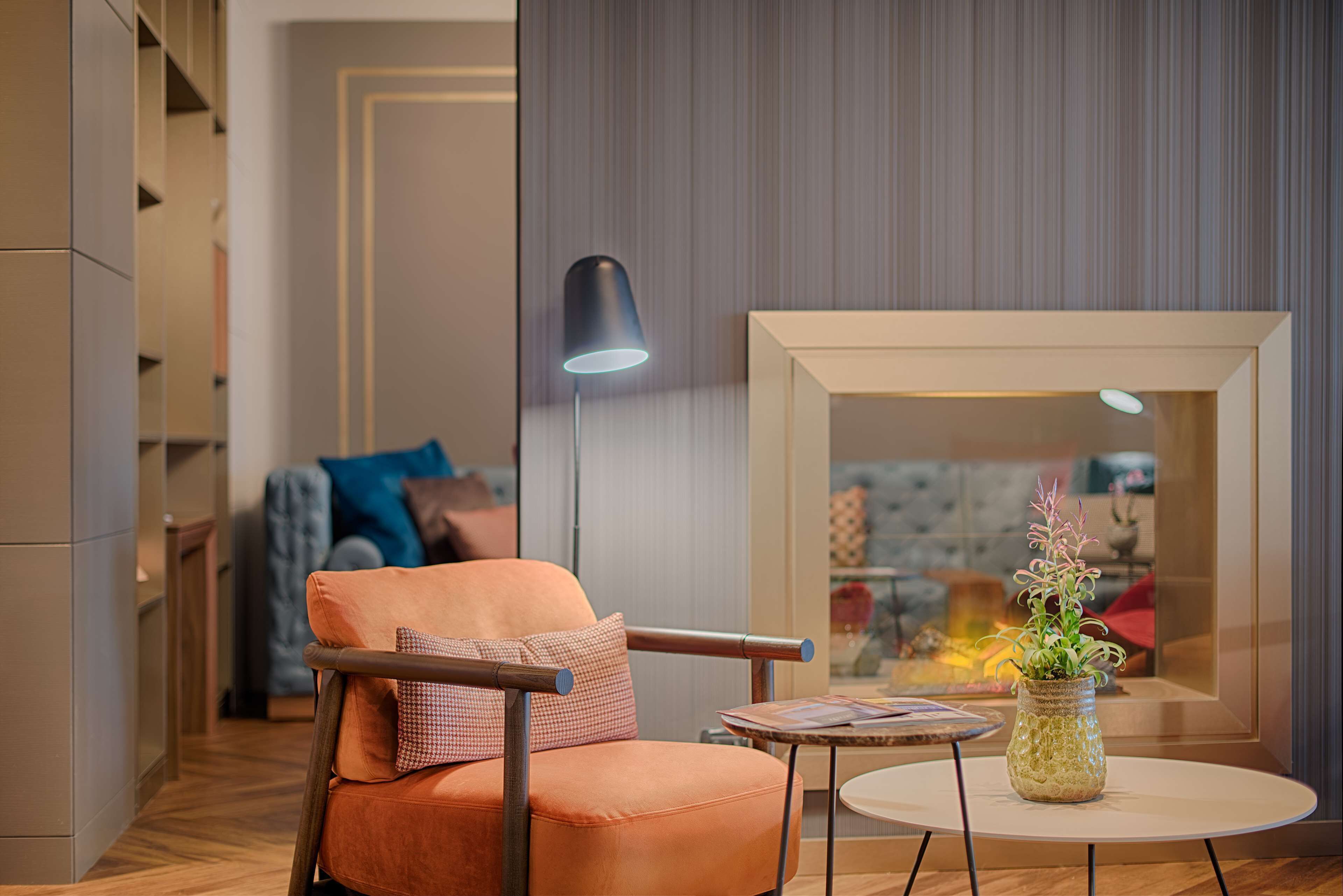 Een moderne woonkamer met een leren fauteuil, een klein rond tafeltje en een vloerlamp.