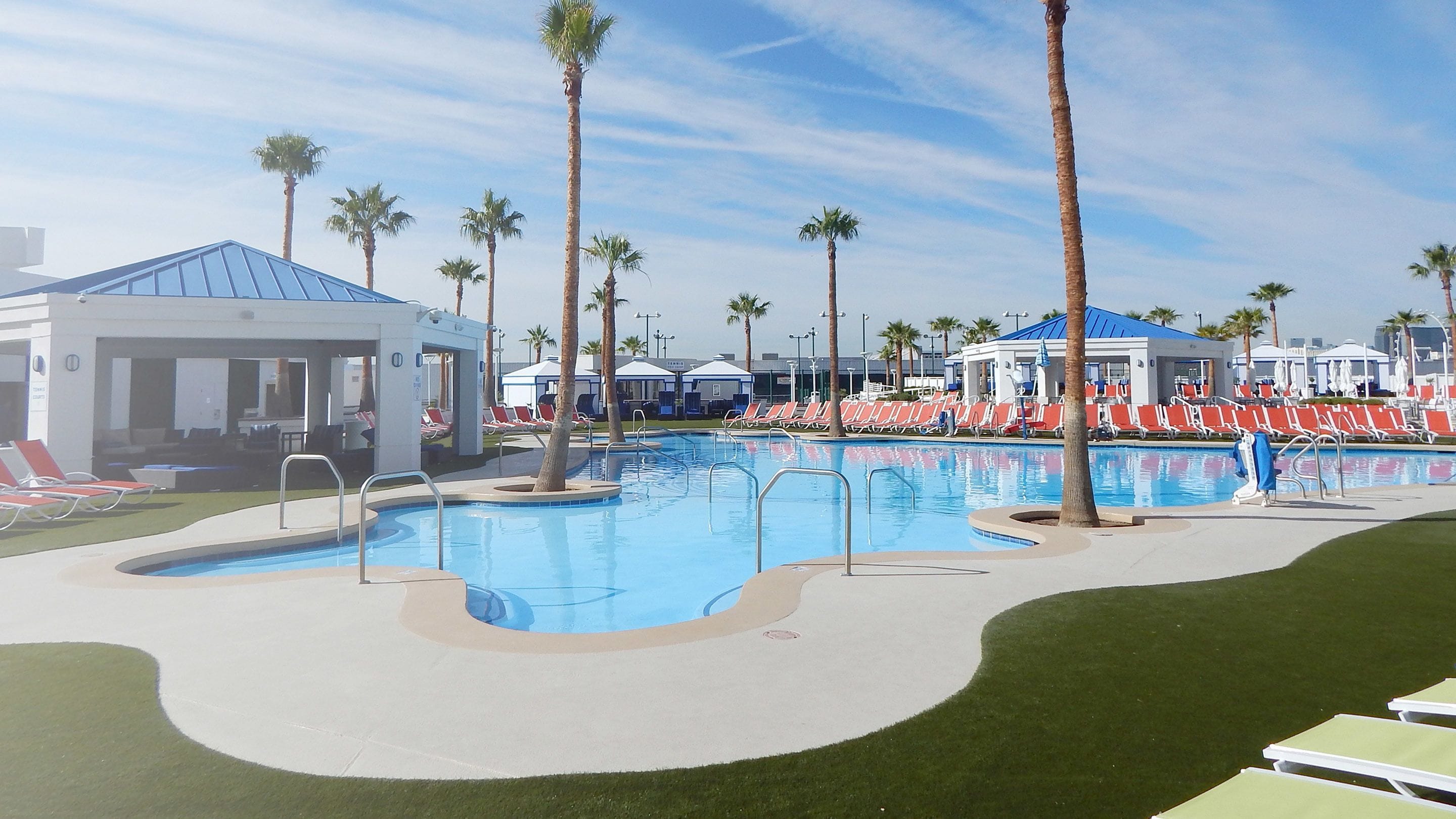 A swimming pool with lounge chairs and palm trees.