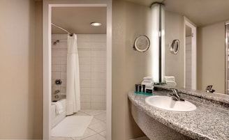Ein modernes Badezimmer mit Dusche, Badewanne und einem Waschtisch auf einer Granittafel.