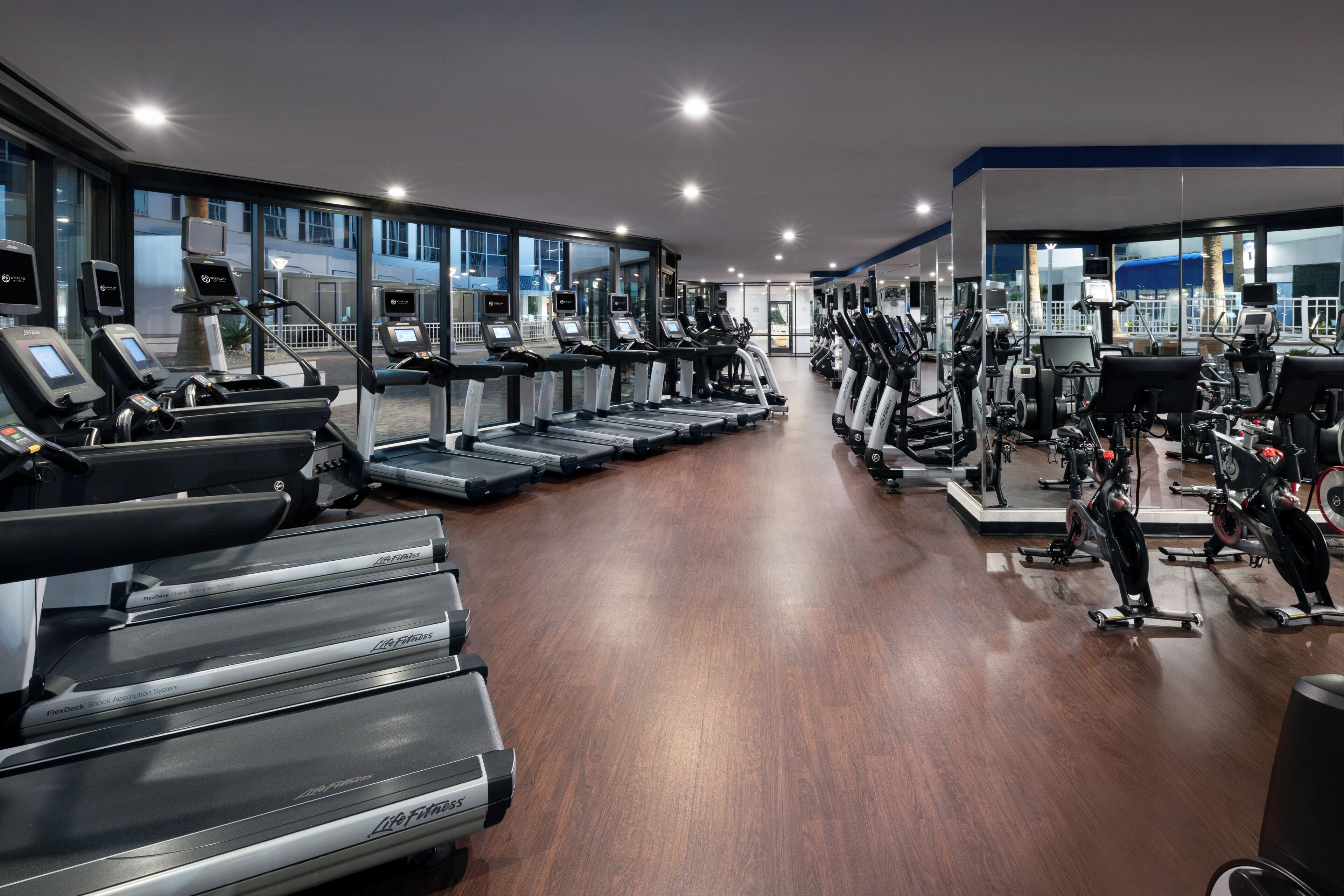 Un gimnasio con cintas de correr, elípticas y bicicletas estáticas.