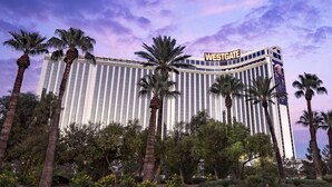 Un hotel grande con un llamativo letrero 'WESTGATE', rodeado de palmeras y un jardín ajardinado.