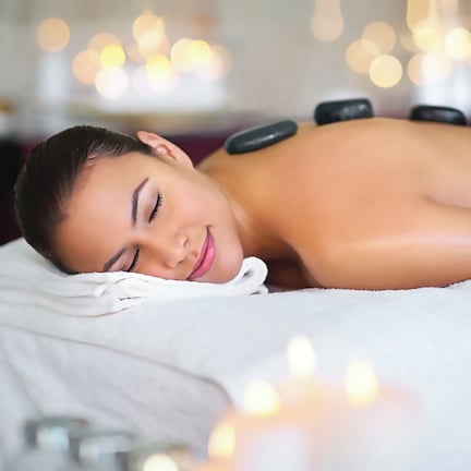 A person receiving a hot stone massage with stones placed on their back.