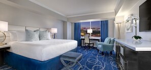 A hotel room with a large bed, a desk, a chair, and a view of the cityscape. - Westgate Las Vegas Resort & Casino (Las Vegas)