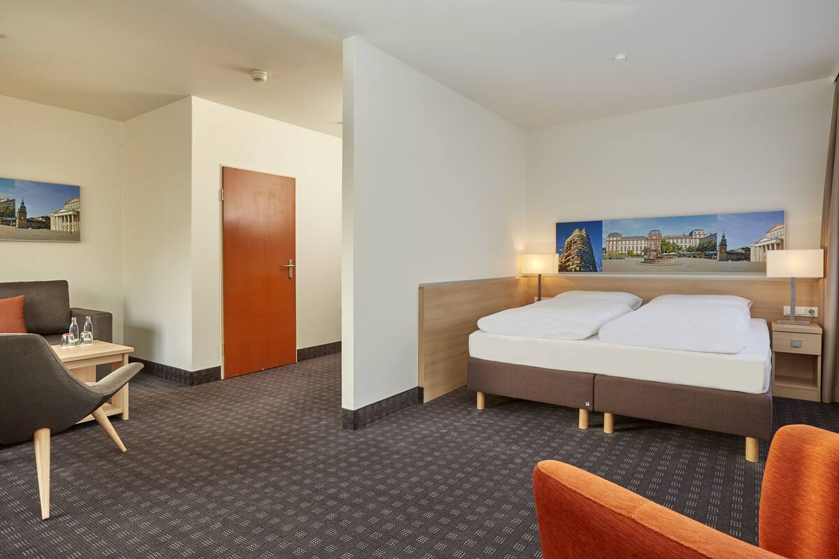 Une chambre d’hôtel avec un lit, un bureau, une chaise et un tableau au mur.