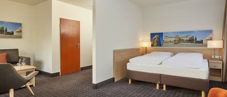 Ein Hotelzimmer mit einem Bett, einem Schreibtisch, einem Sessel und einem Gemälde an der Wand.