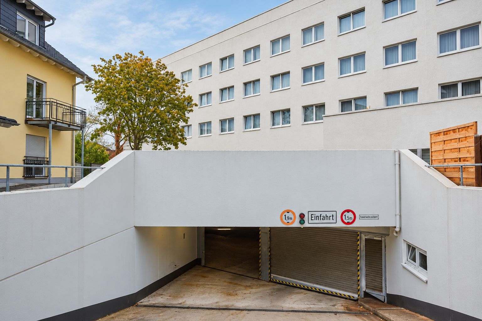 A building with a covered entrance, a tree, and a sign indicating a height limit of 1.9 meters.