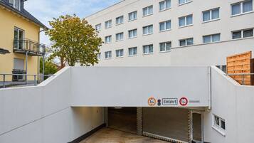 A building with a covered entrance, a tree, and a sign indicating a height limit of 1.9 meters.