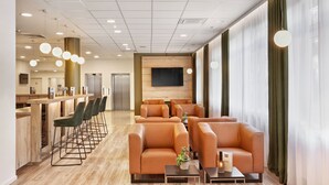 A modern hotel lobby with a bar area, seating, and a flat-screen TV.