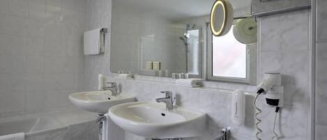 A modern bathroom with two sinks, a mirror, and a hairdryer.