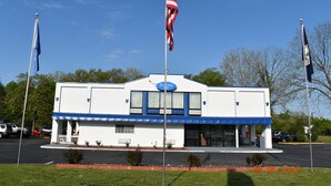 A building with a blue and white facade, a sign reading "Economy Inn," and two American flags on flagpoles.