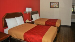 A hotel room with two beds, red walls, and a small painting on the wall.